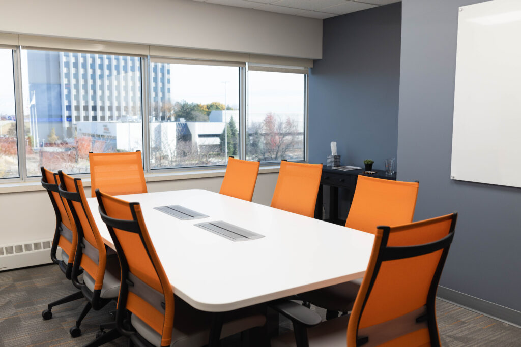 Office Evolution conference room with 8 orange chairs and a view of the city