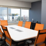 Office Evolution conference room with 8 orange chairs and a view of the city
