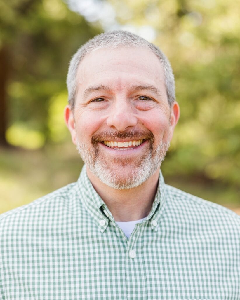 Smiling mature man outdoors in business casual attire, promoting professional workspaces and office solutions.