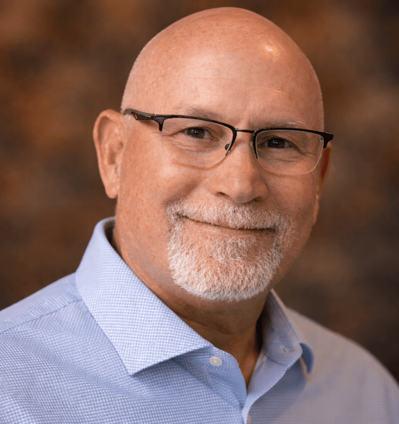 Professional middle-aged man with glasses smiling in a business portrait.
