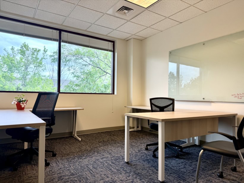 Office Evolution coworking space with desks and chairs, bright natural light, and a whiteboard for m.