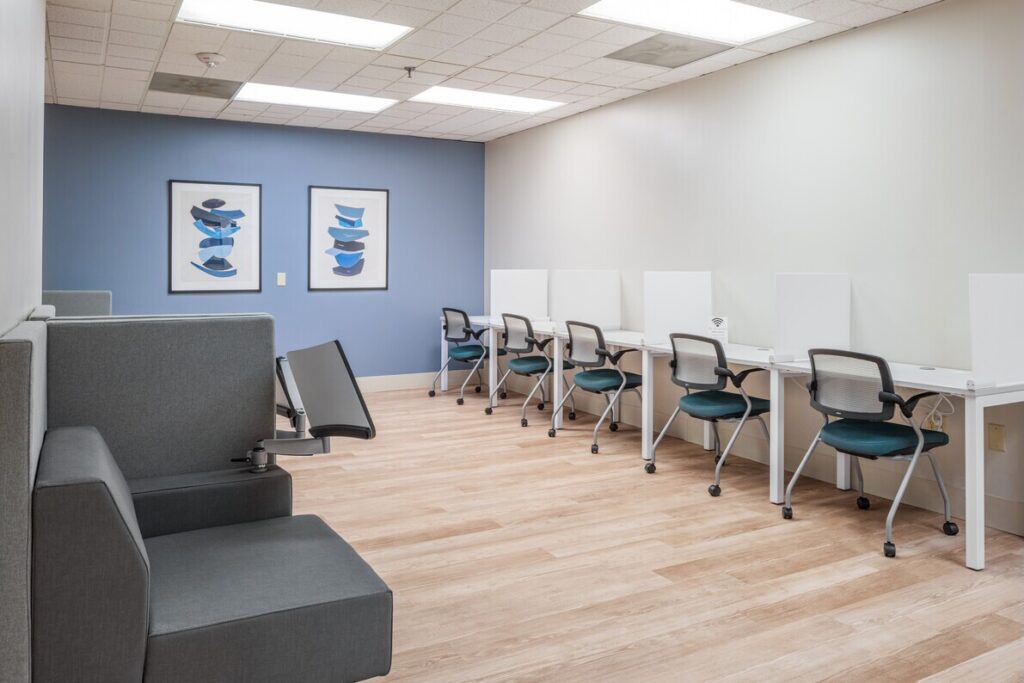 Drop in space with row of work stations and teal chairs.