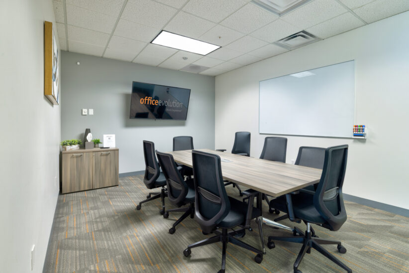 Modern office conference room with meeting table, whiteboard, and Office Evolution branding.