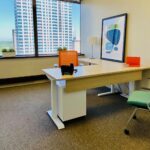 Private office space with adjustable desk and orange decor.