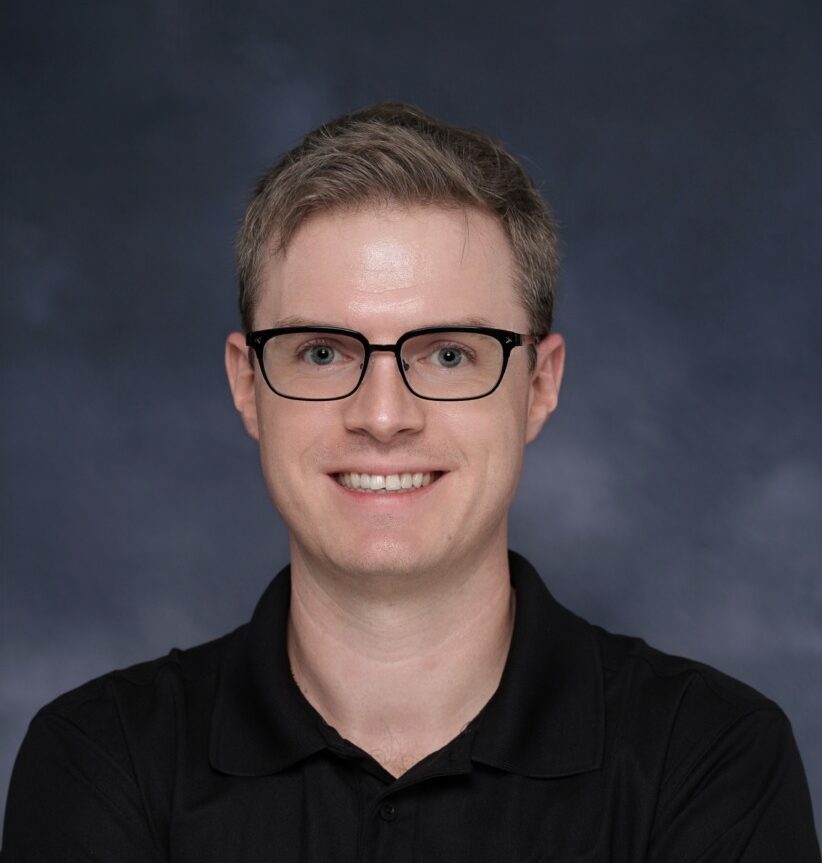 Professional man in black polo with Office Evolution logo, smiling confidently.