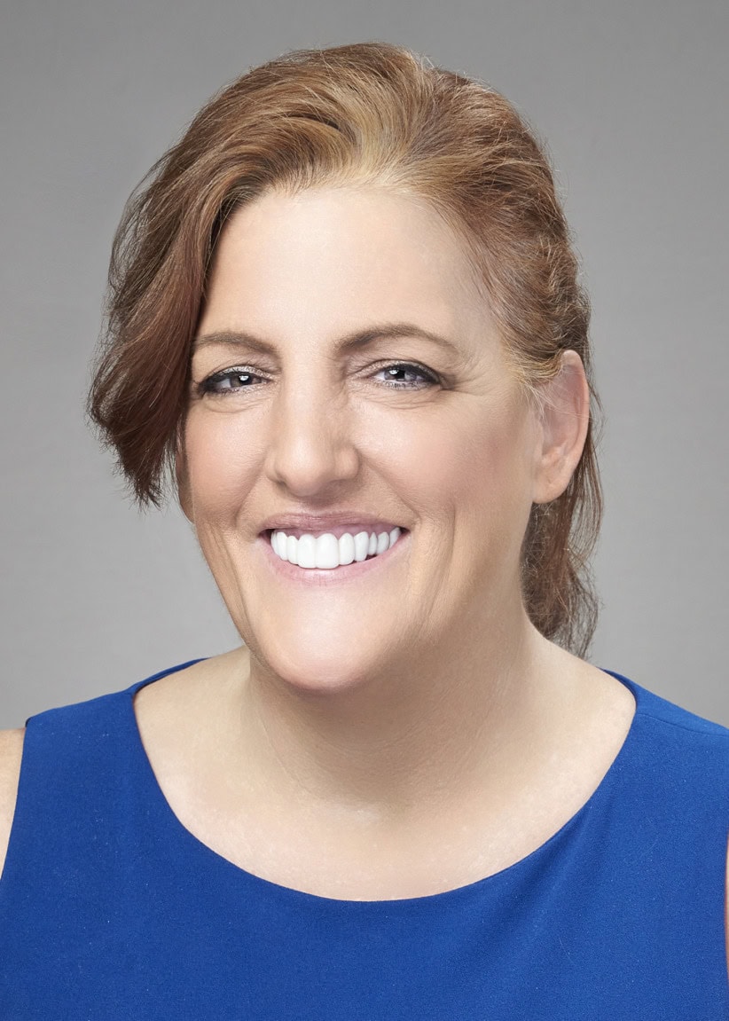 A woman smiling in a professional setting, representing coworking and office solutions.