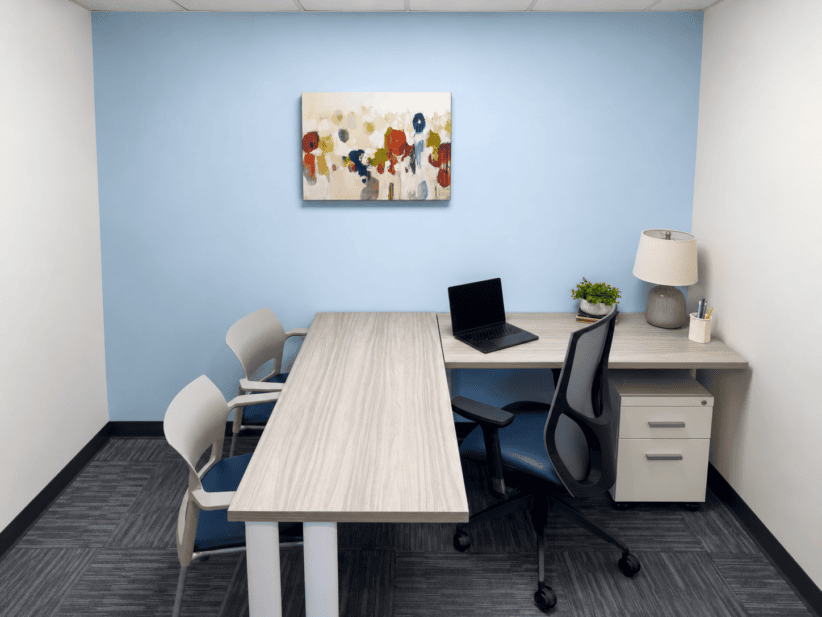Modern office meeting room with blue wall, artwork, and workspace furniture.