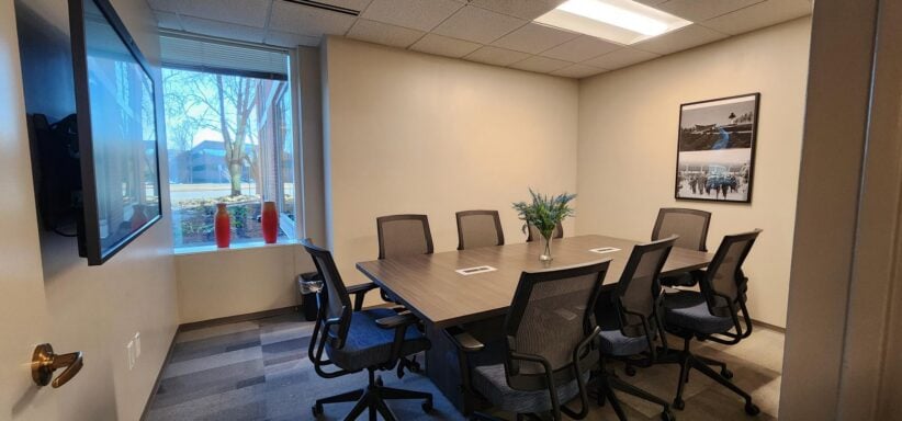 Modern office meeting room with large window, conference table, and comfortable chairs for coworking.