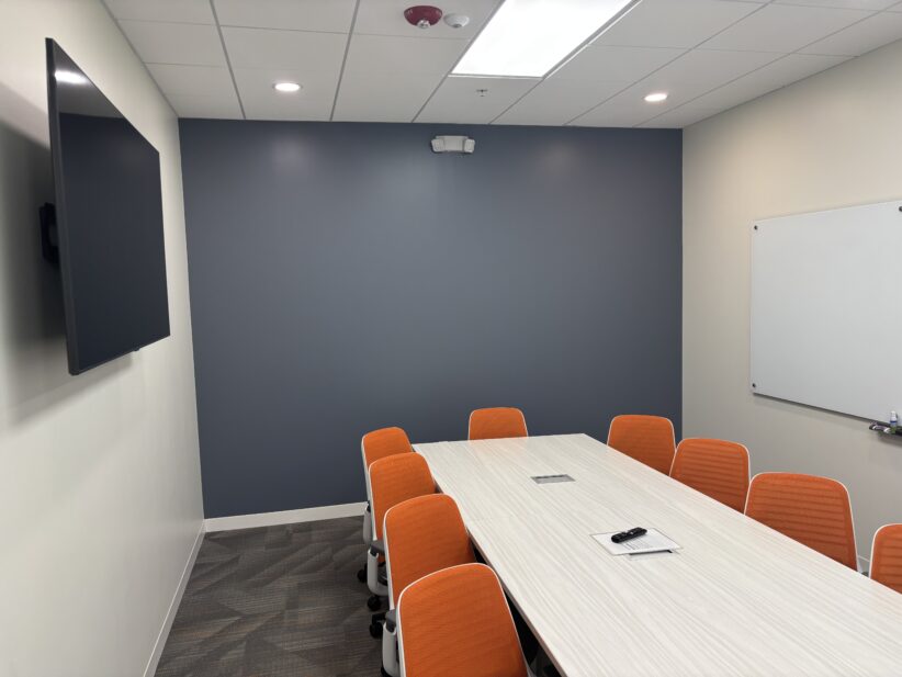 Comfortable modern conference room with orange chairs and whiteboard at Office Evolution.