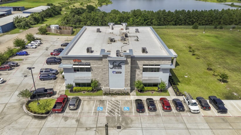 Modern office building with accessible parking and surrounding greenery for coworking and business services.