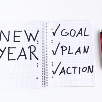 a not pad that says: New year and a checklist with goals,plan,action