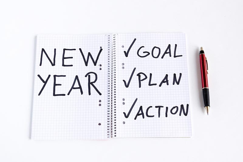 a not pad that says: New year and a checklist with goals,plan,action