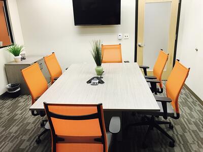 Conference room table with orange chairs.