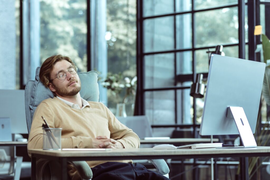 Job hunting in the tech industry requires patience and persistence. Image of tired man at desk with computer in front of him.