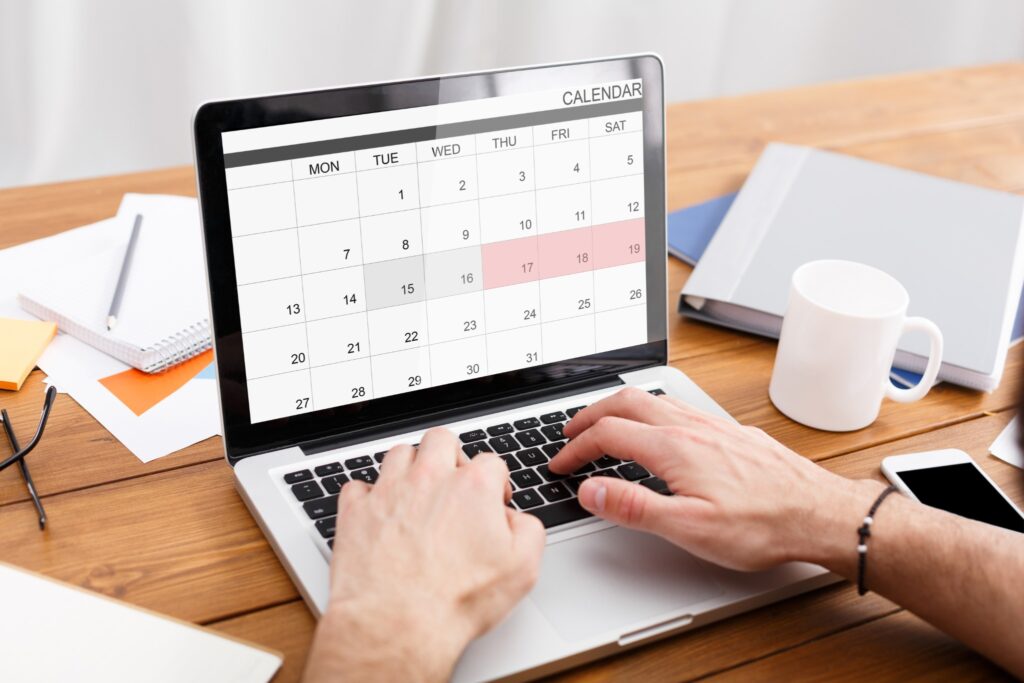 Image of person updating their digital calendar on a laptop.