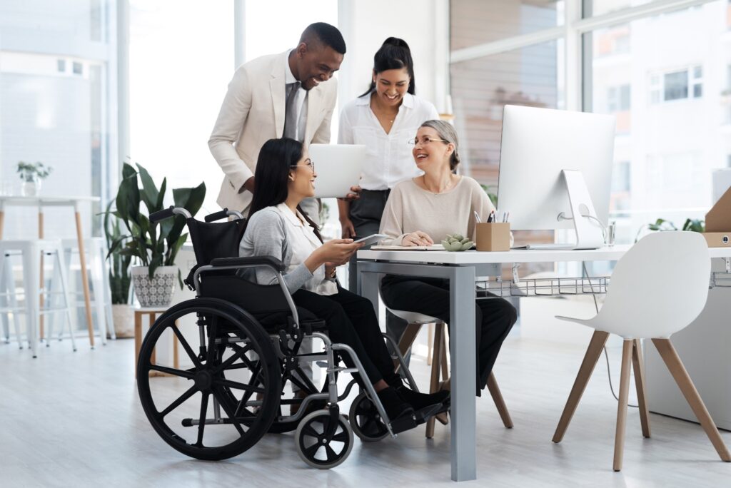 Coworking spaces support inclusion and belonging in the workplace by offering the freedom to choose how you interact with others in the space. Image of four diverse colleagues working at a table.