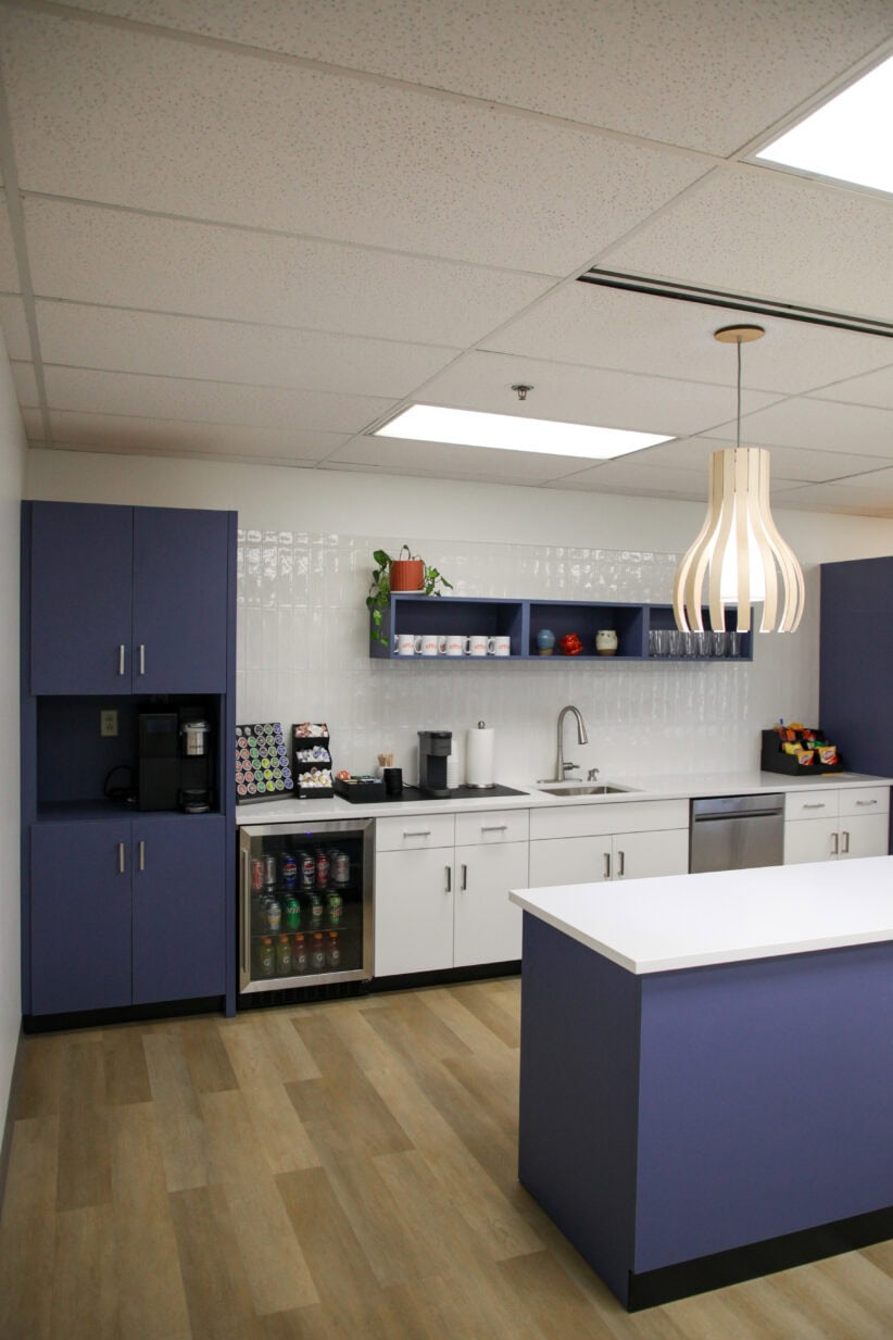 Beautiful modern kitchenette with blue and white cabinets at Office Evolution coworking space, ideal for breaks and informal meetings.