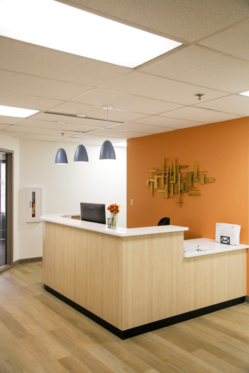 Modern office reception desk with warm wood finish at Office Evolution coworking space, professional workspace environment.