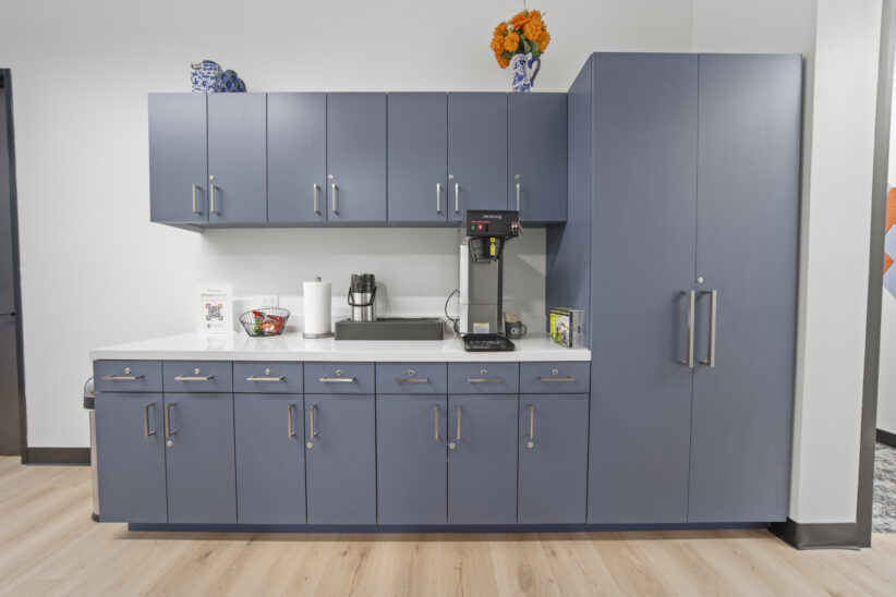 Modern office break room with blue cabinets and coffee station, ideal for coworking spaces and business offices.