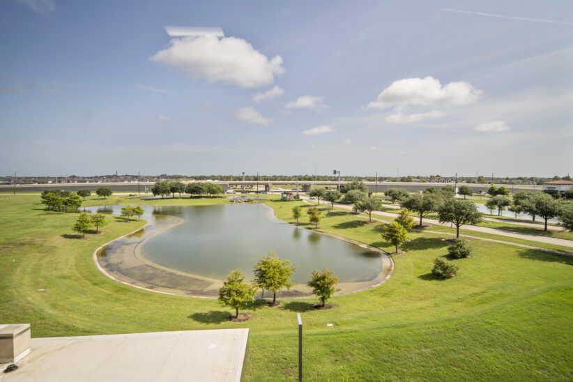Serene office view with a pond, green trees, and modern surroundings at Office Evolution.