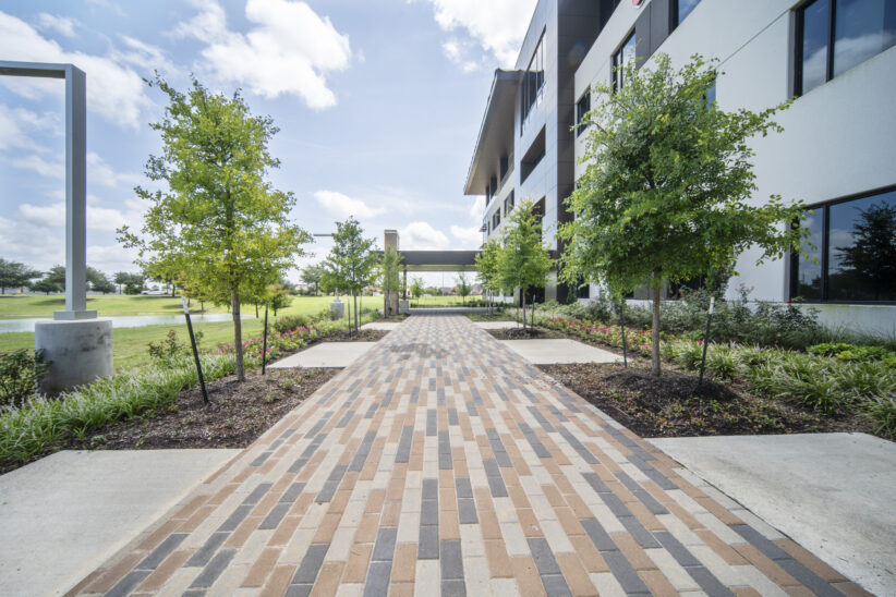 Modern office building with outdoor workspace and landscaped pathways for professional meetings and remote work.
