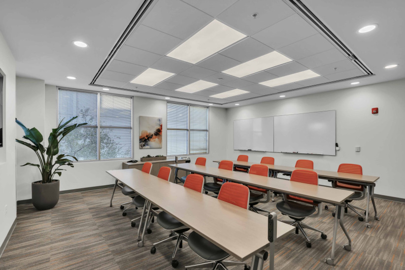 Modern corporate training room with desks, orange chairs, and whiteboards | Office Evolution.