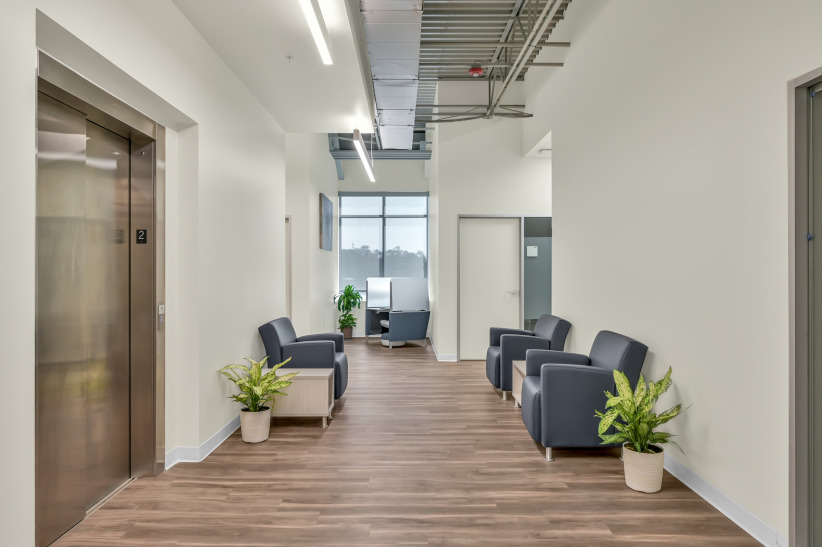 Modern office lobby with elevator, seating area, and plants for professional workspace comfort.