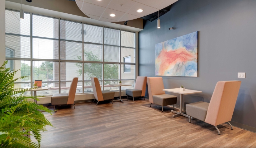 Modern office lounge with large windows, comfortable seating, and stylish decor, ideal for remote work or meetings.