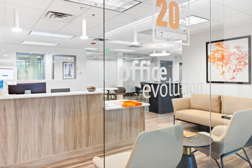 Modern office reception area with comfortable seating and glass walls for coworking space or business meetings.