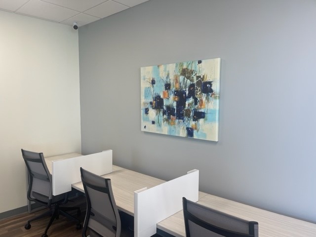 Modern office meeting room with collaborative workspace and abstract art decor.