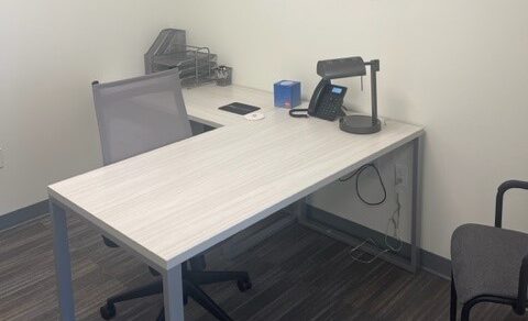 Modern office workspace with desk, chair, phone, and office supplies for flexible business solutions.