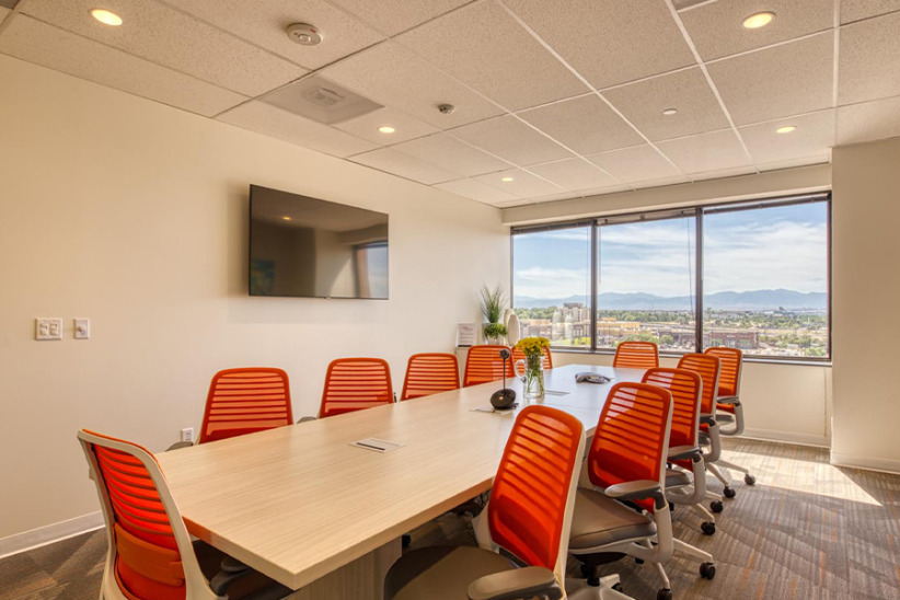 Modern office conference room with large windows and ergonomic orange chairs for productive meetings and collaboration.