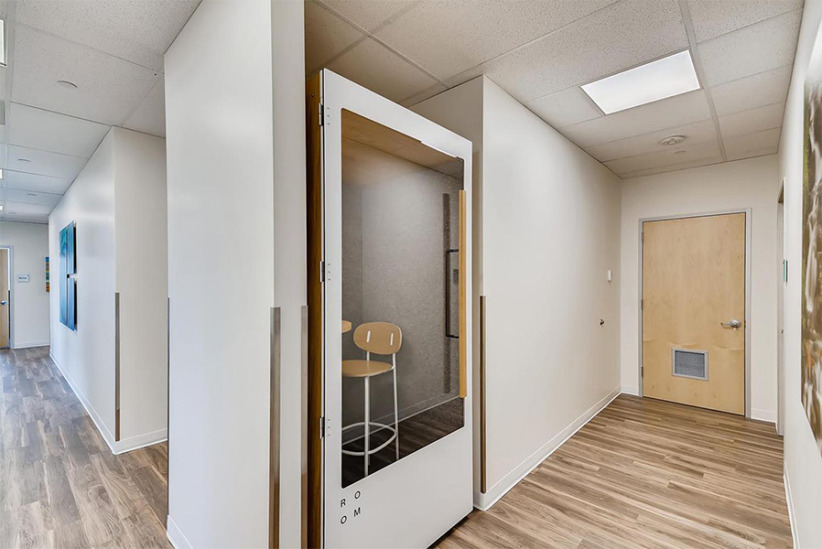 Modern office space with private phone booth and hallway for remote work and meetings.