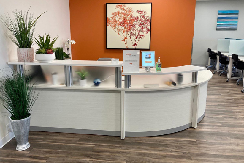 Modern office reception desk at Office Evolution with plants and a welcoming atmosphere.