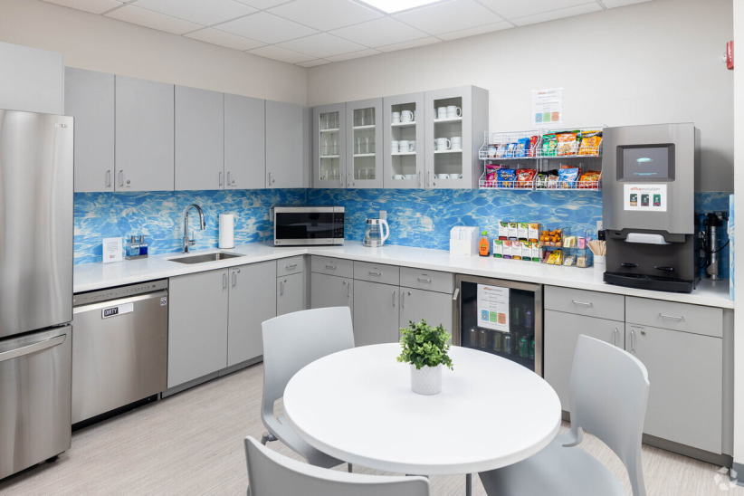 Modern office kitchenette with coffee machine and snack station for remote work and meetings.