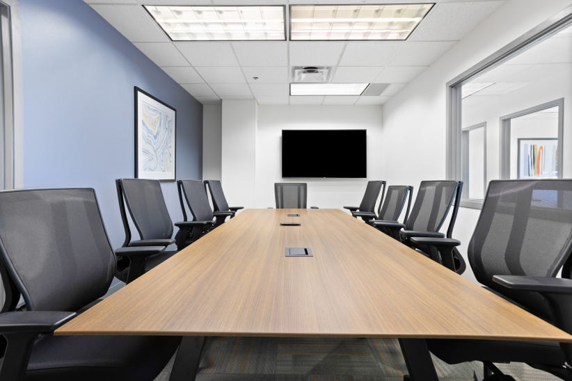 Conference room with modern office furniture and large screen for meetings and collaboration, within a professional coworking space.
