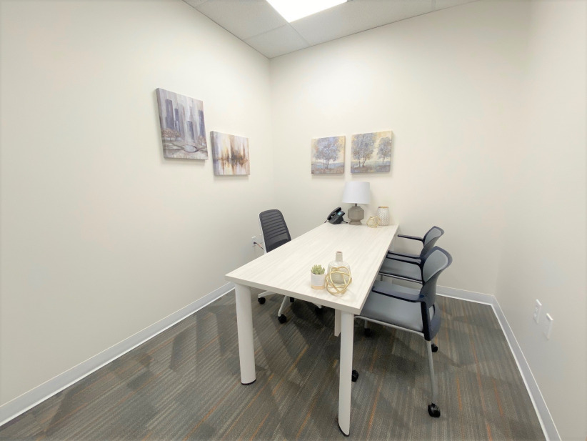 Modern office meeting room with minimal decor, comfortable chairs, and natural light for productive work.