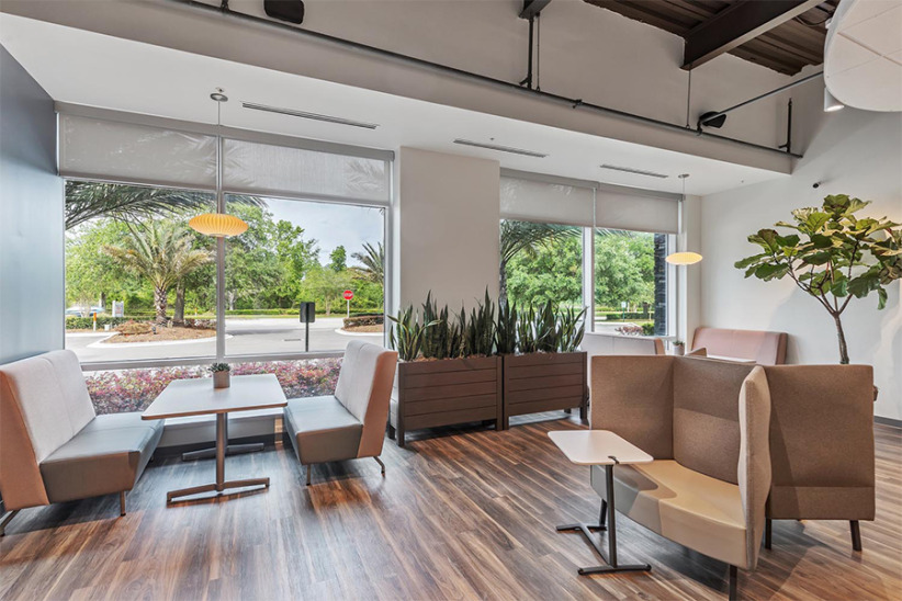Modern office lounge area with comfortable seating and large windows, perfect for relaxation and informal meetings.