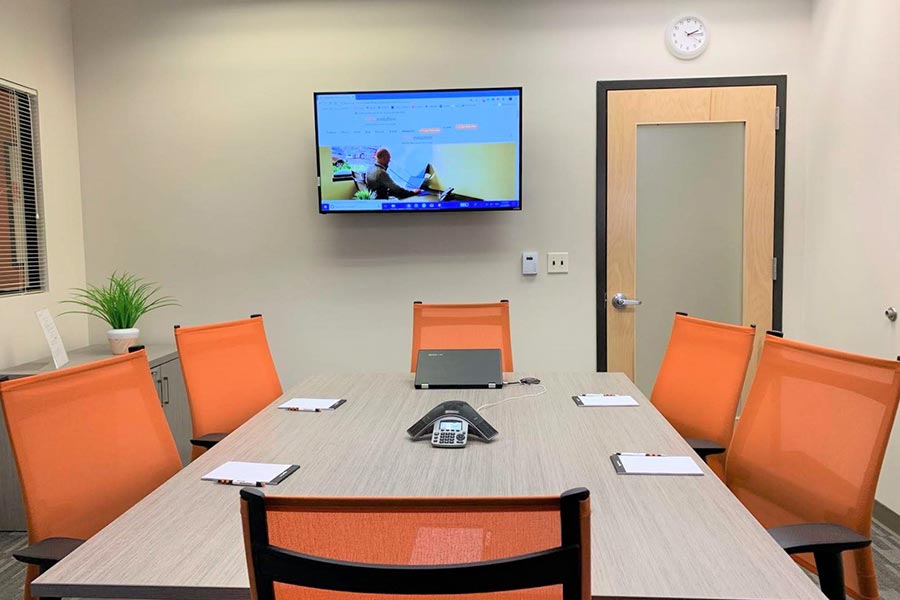 Modern conference room with office desks, chairs, and presentation technology.