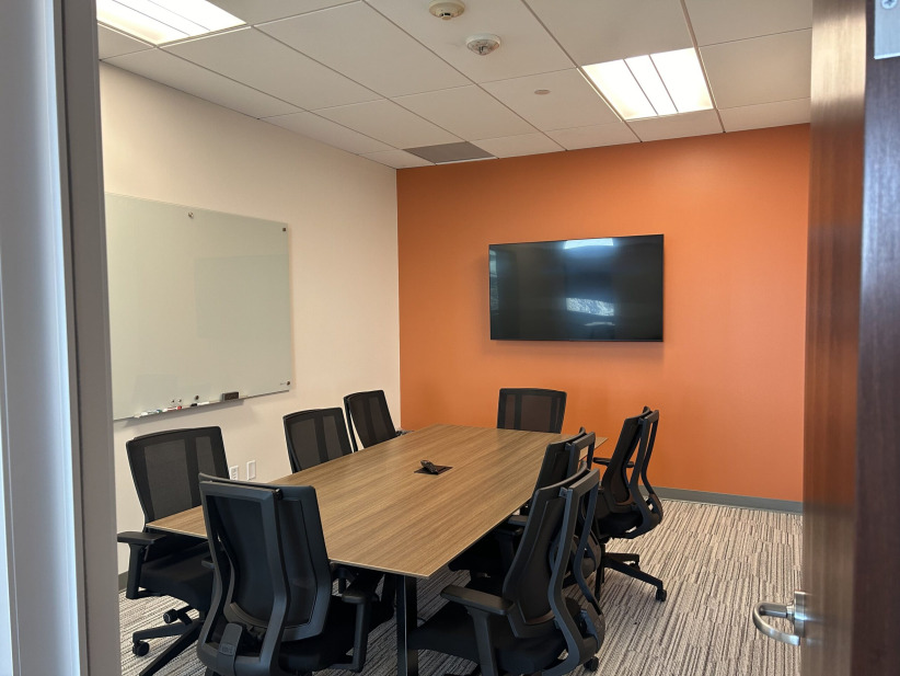 Meeting room with modern office furniture and large TV for presentations and video conferencing.