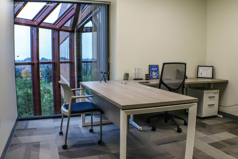 Office evolution private office workspace with window view.