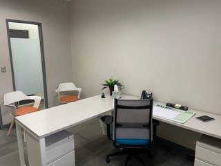 Modern office workspace with a white desk, ergonomic chair, and minimal decor.