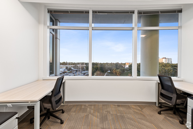 Office space with large windows and modern desks for coworking or private work.