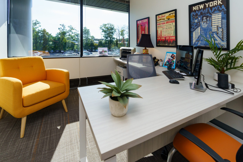 Modern coworking office space with large window and vibrant decor, ideal for remote work and meetings.
