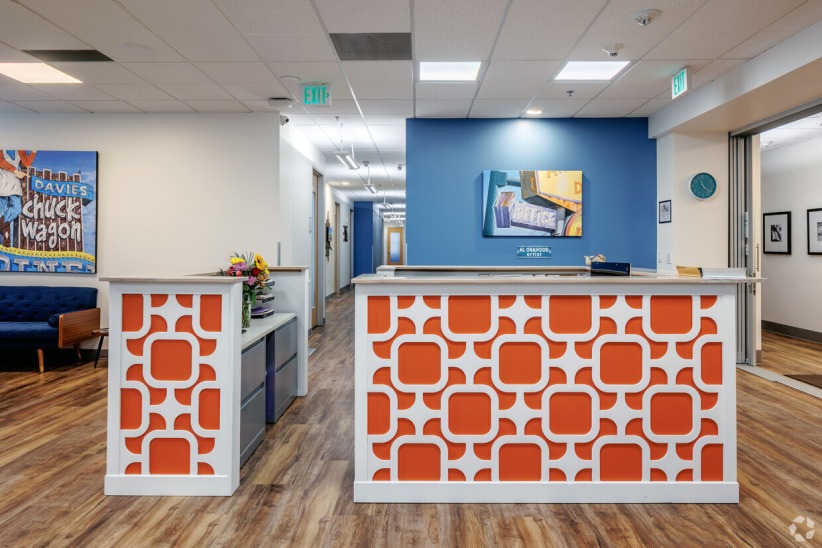 Modern office reception area with bright orange geometric accents, fostering professional and welcoming business environment.