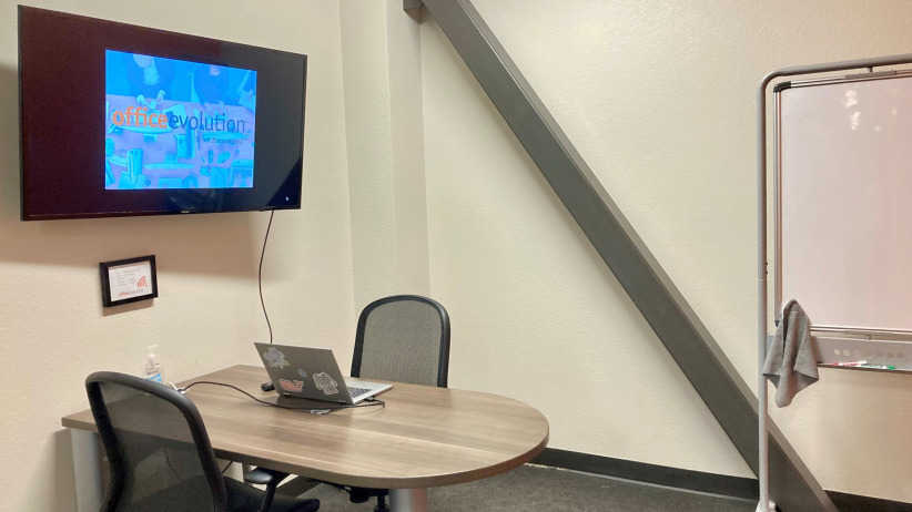 Office evolution coworking space with meeting table and whiteboard at office, modern workspace interior, professional business environment.