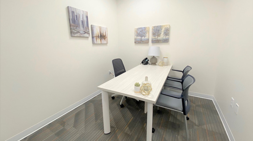 Modern office meeting room with a white conference table and comfortable chairs, ideal for coworking or business meetings.