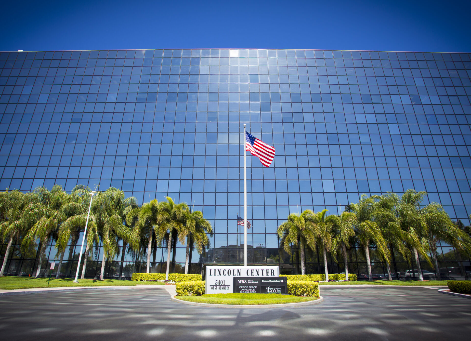 Modern office building with reflective glass exterior and an American flag, representing flexible workspace solutions.