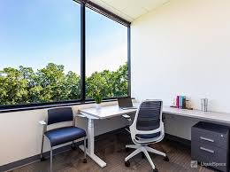 Modern office workspace with large window and ergonomic chair, ideal for productivity and professional meetings.