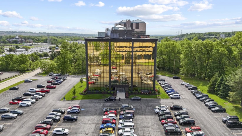 Modern office building with reflective glass facade and surrounding parking lot.